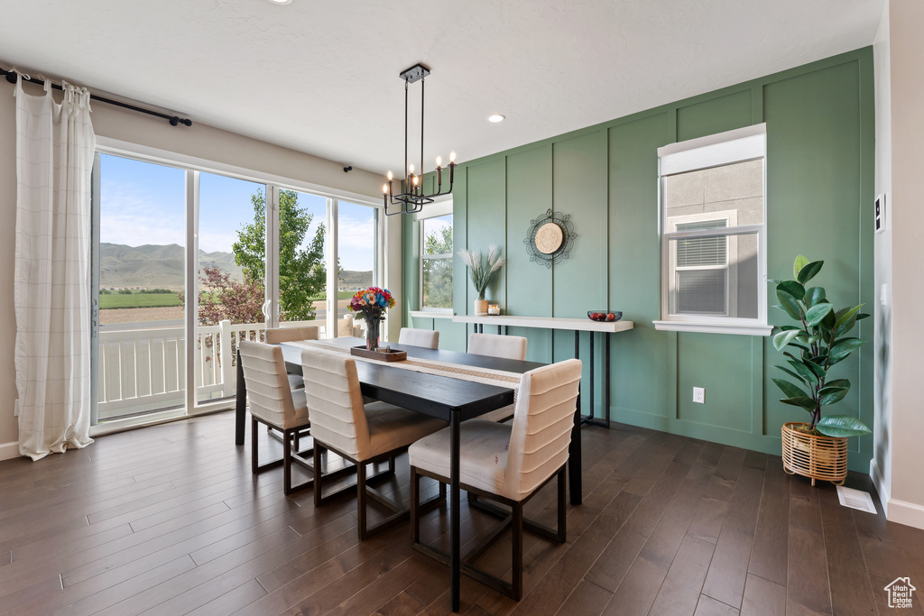 Dining space featuring a decorative wall, a mountain view, dark wood-type flooring, a chandelier, and baseboards