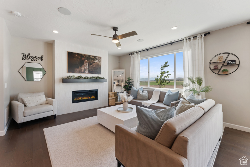 Living area featuring a glass covered fireplace, ceiling fan, baseboards, dark wood-style flooring, and recessed lighting