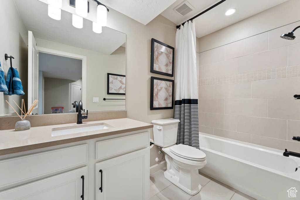 Bathroom featuring shower / tub combo with curtain, vanity, tile patterned floors, toilet, and baseboards