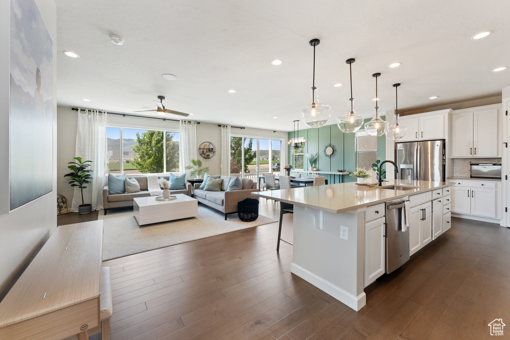 Kitchen featuring stainless steel appliances, a sink, open floor plan, recessed lighting, and white cabinets