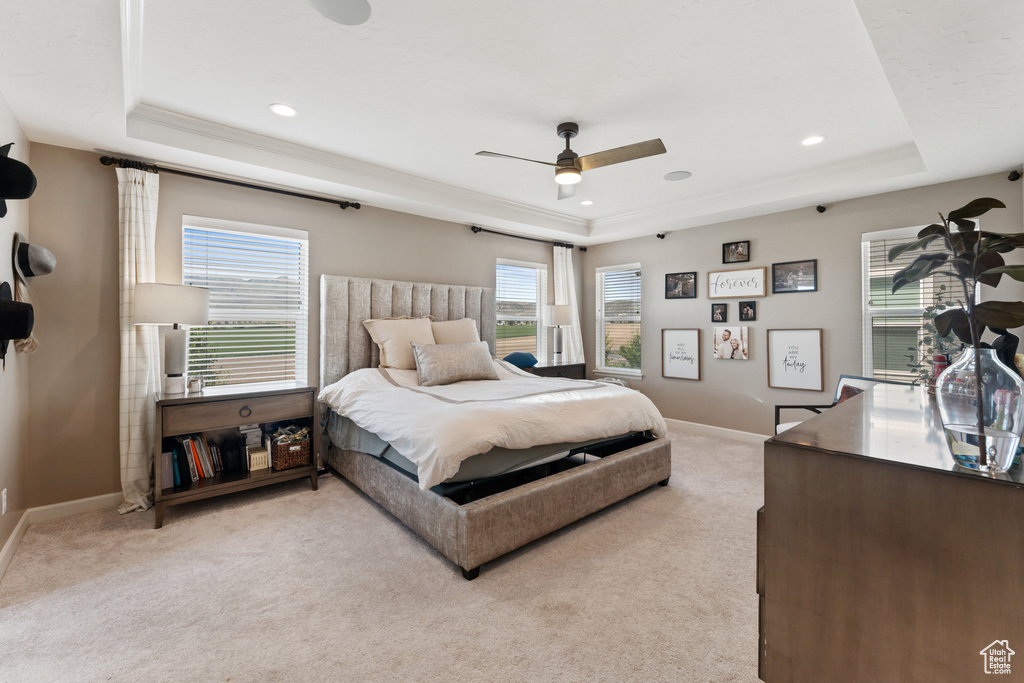 Bedroom with a raised ceiling, light carpet, baseboards, recessed lighting, and a ceiling fan
