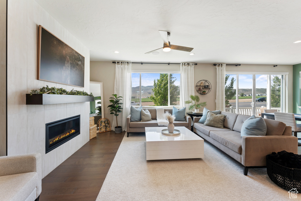 Living area with plenty of natural light, wood finished floors, ceiling fan, a tile fireplace, and recessed lighting