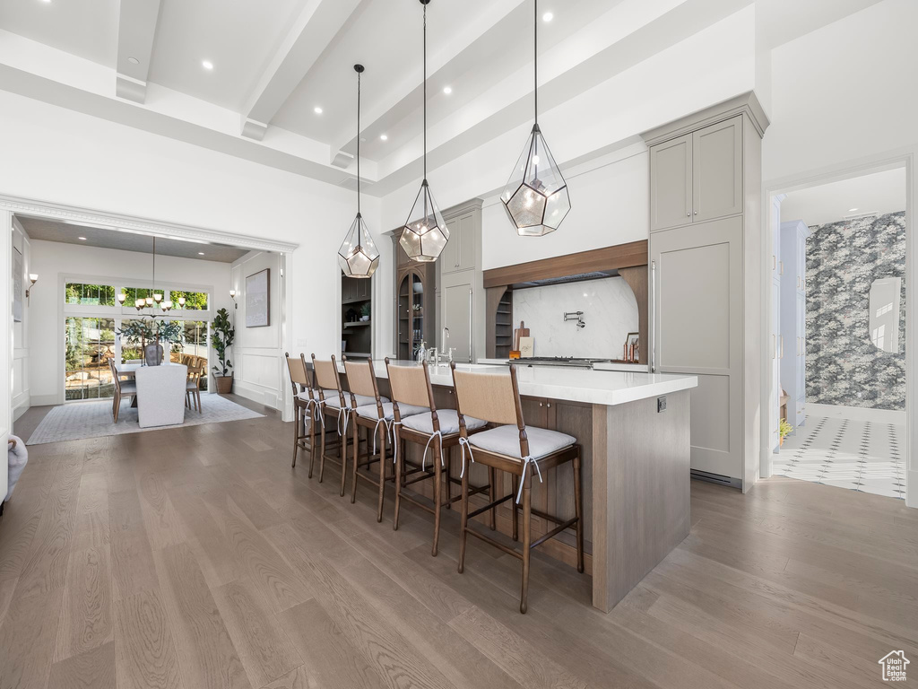 Kitchen with a large island, wood finished floors, light countertops, gray cabinetry, and beamed ceiling