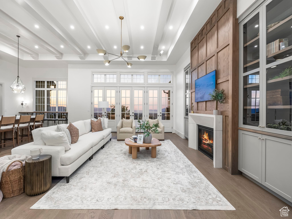 Living area with a large fireplace, wood finished floors, a chandelier, recessed lighting, and french doors