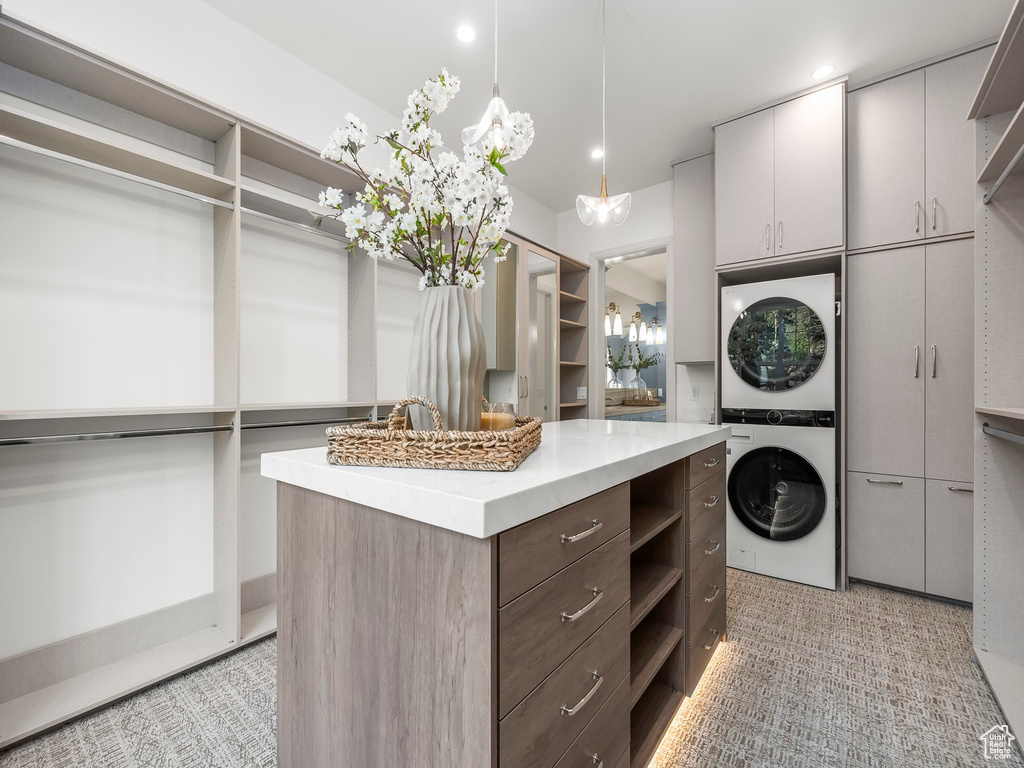 Walk in closet featuring stacked washer / dryer and light carpet