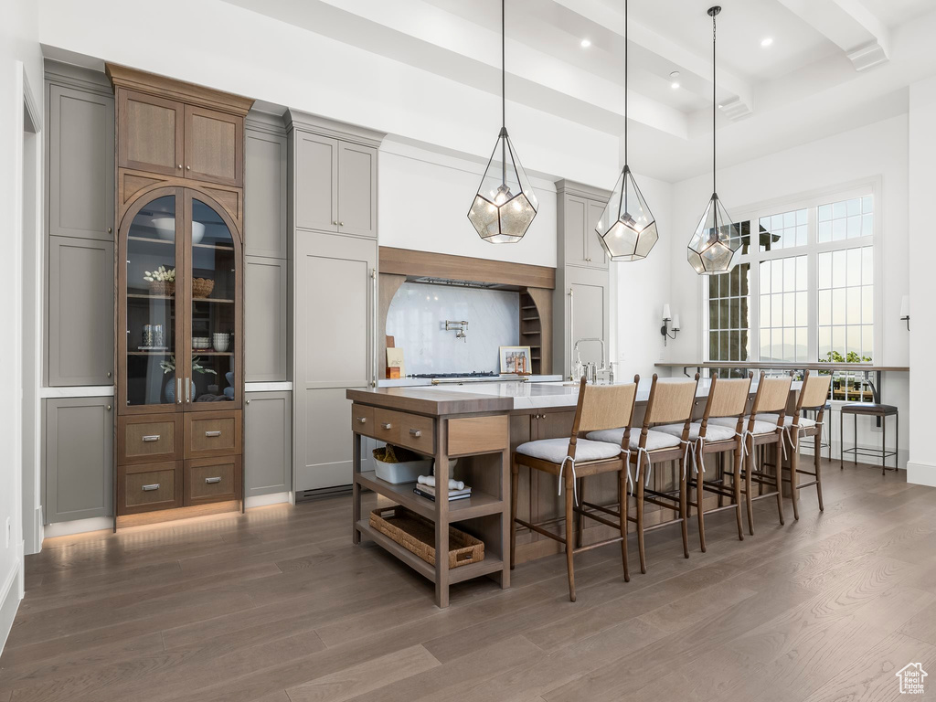 Kitchen featuring wood finished floors, a large island, a kitchen breakfast bar, recessed lighting, and decorative light fixtures