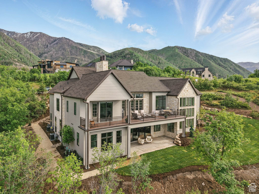 Rear view of house featuring a patio, a mountain view, cooling unit, a chimney, and roof with shingles