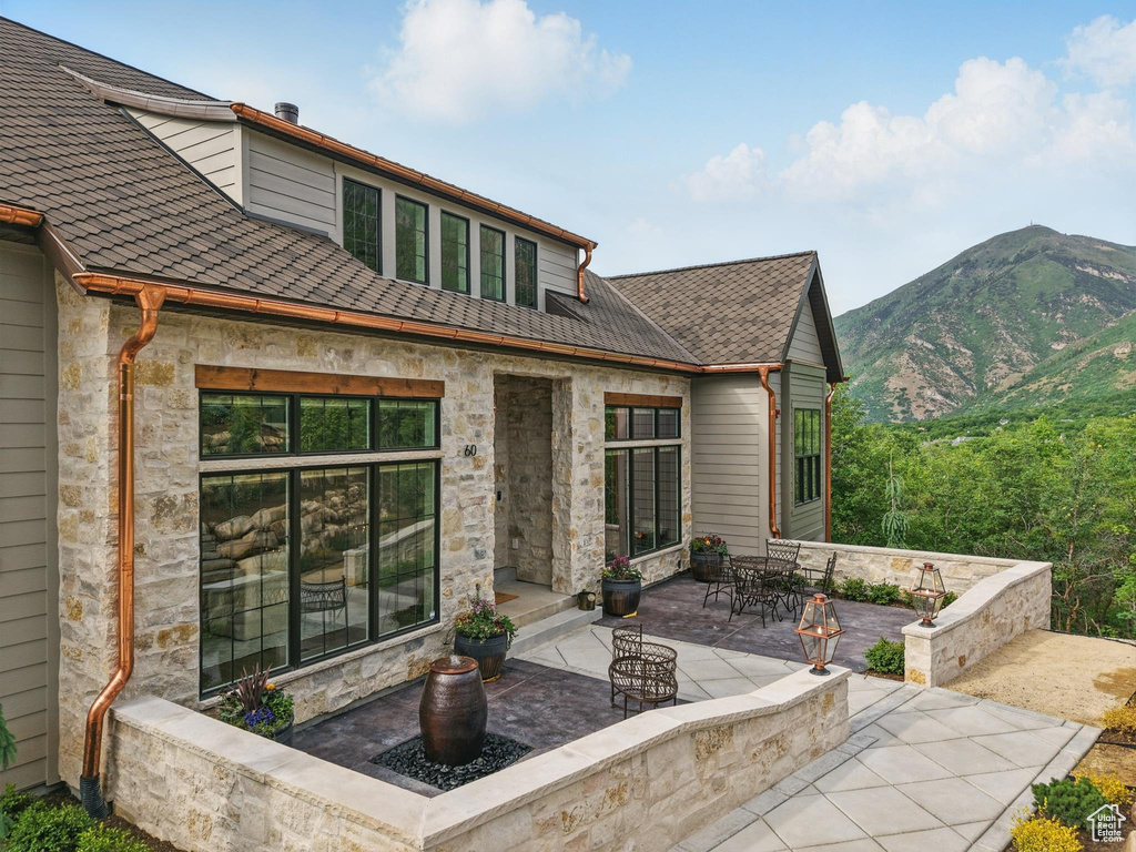Back of property with a patio area, stone siding, and a mountain view