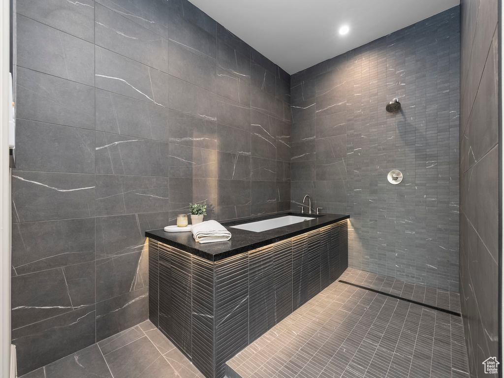 Bathroom featuring tile walls, a sink, tile patterned floors, a garden tub, and tiled shower