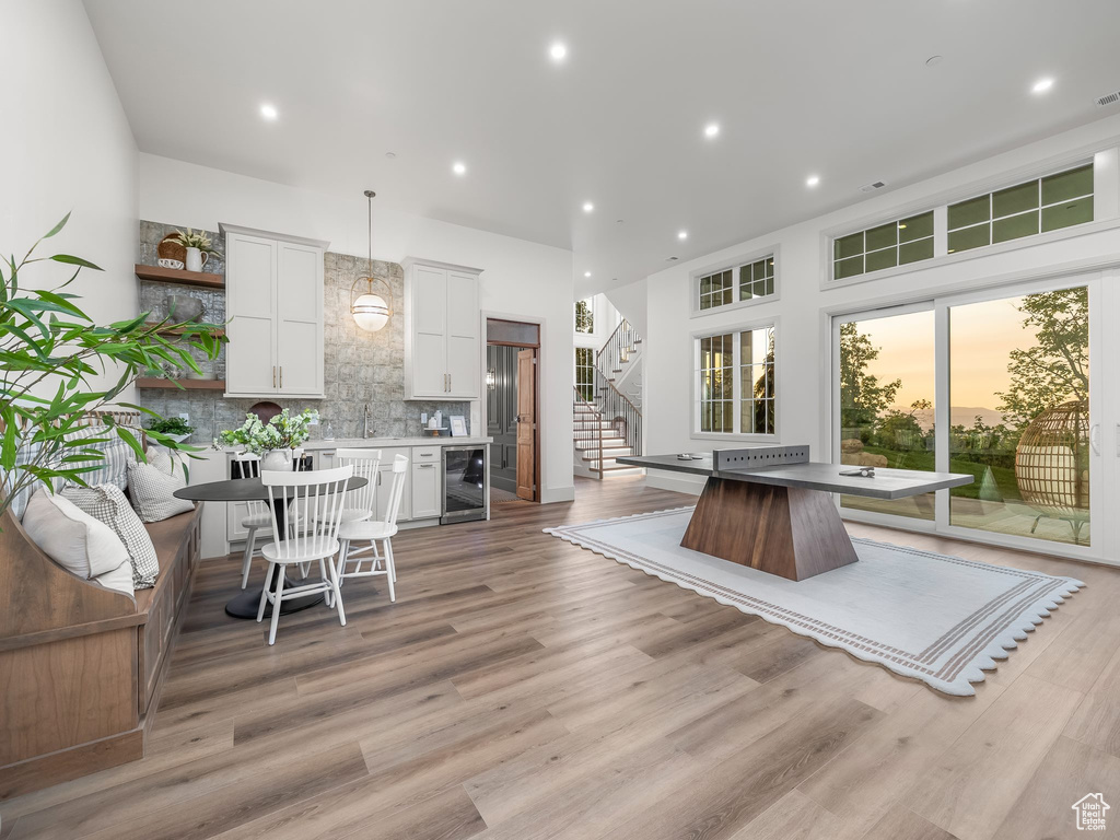 Kitchen with wine cooler, backsplash, white cabinets, light wood-style flooring, and open shelves
