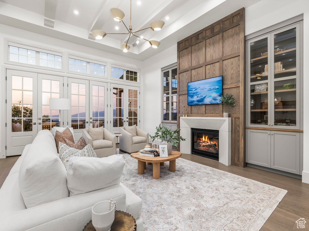 Living area featuring french doors, wood finished floors, a glass covered fireplace, a chandelier, and recessed lighting
