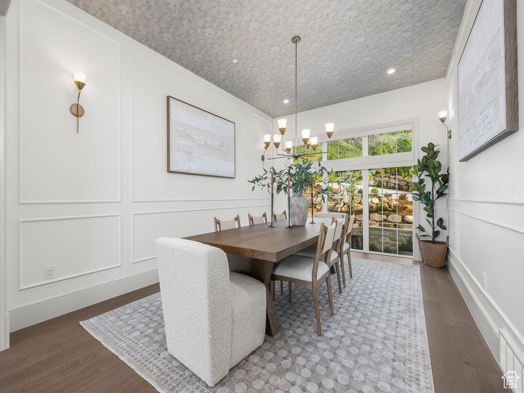 Dining room with a decorative wall, wood finished floors, and a chandelier