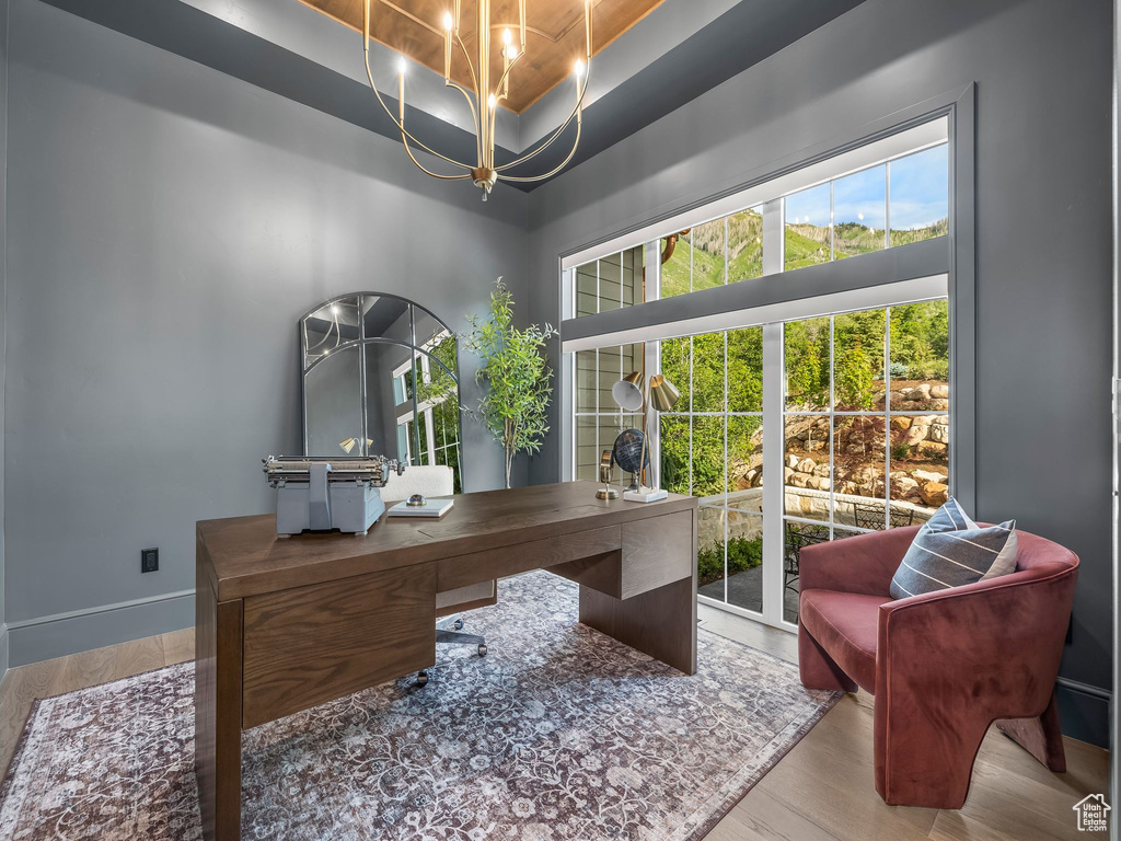 Office space with wood finished floors, a chandelier, a tray ceiling, and baseboards