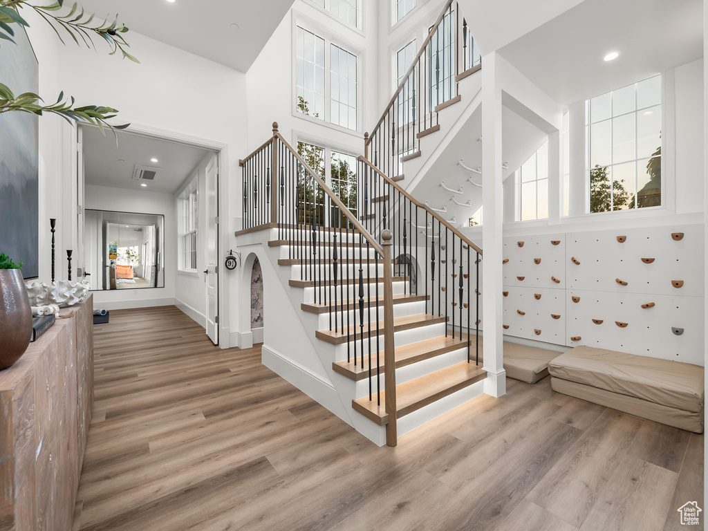Staircase with wood finished floors, a high ceiling, recessed lighting, and baseboards