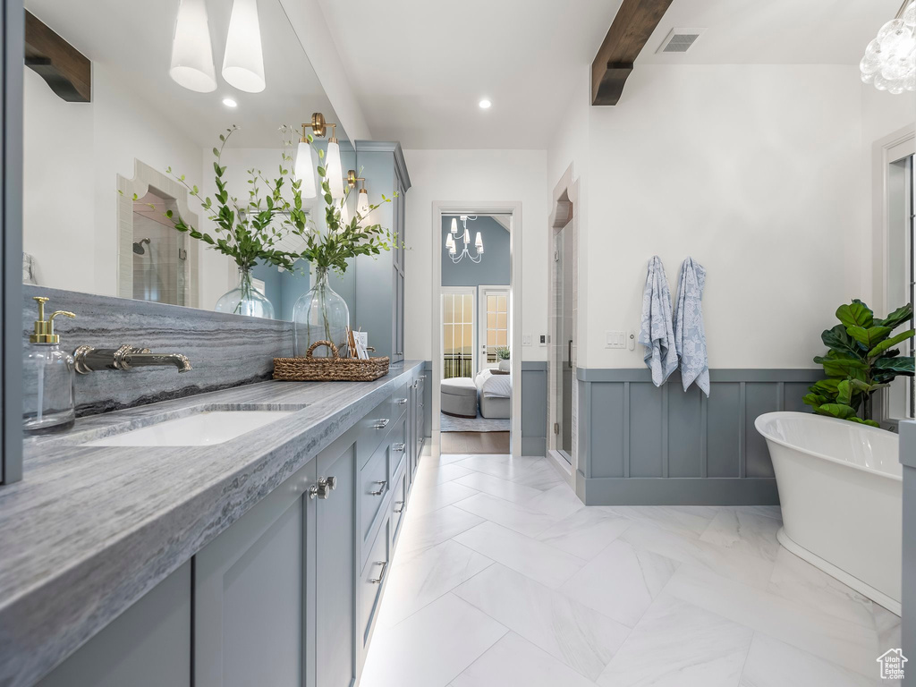 Bathroom featuring double vanity, a freestanding bath, a wainscoted wall, a stall shower, and beam ceiling