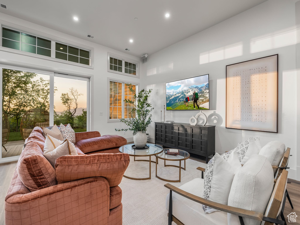 Living room with wood finished floors, recessed lighting, and a towering ceiling