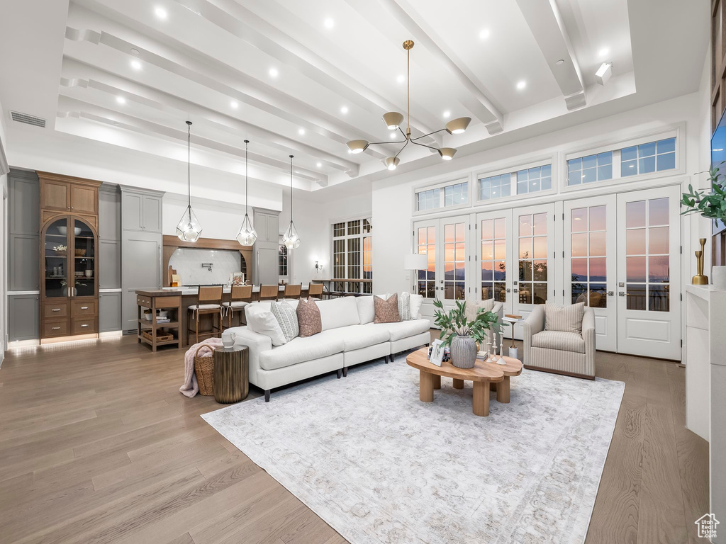 Living area featuring french doors, light wood-style flooring, a chandelier, a high ceiling, and recessed lighting