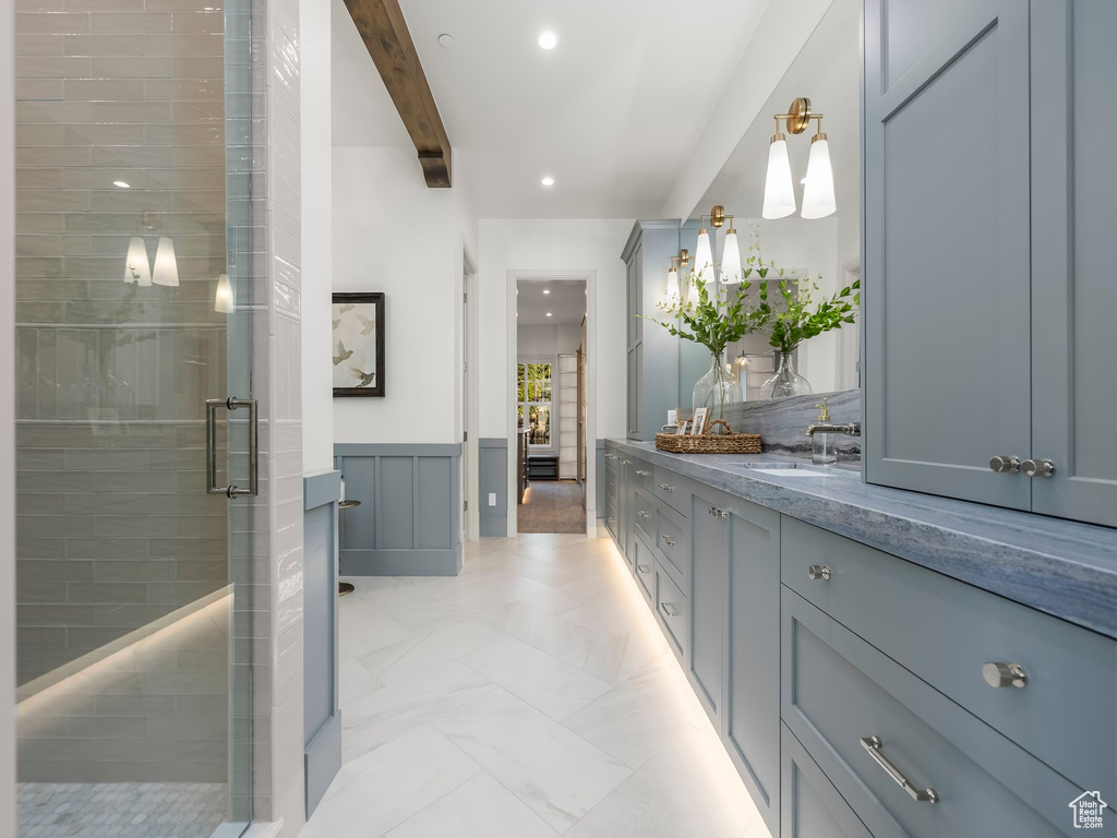 Bathroom with double vanity, a shower stall, a wainscoted wall, recessed lighting, and beam ceiling