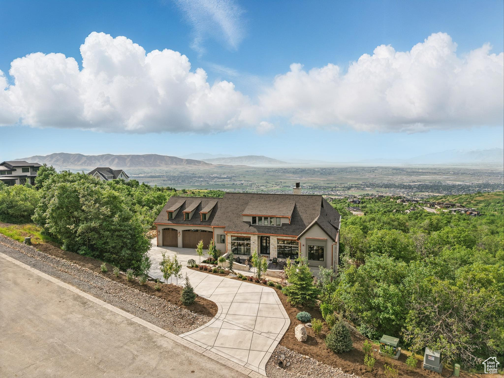 View of front of home featuring curved driveway, a mountain view, and a chimney