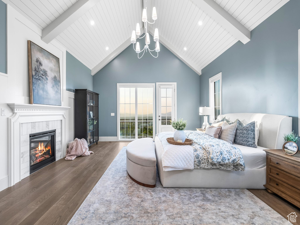 Bedroom featuring wood finished floors, access to outside, a chandelier, wooden ceiling with exposed beams, and a tiled fireplace