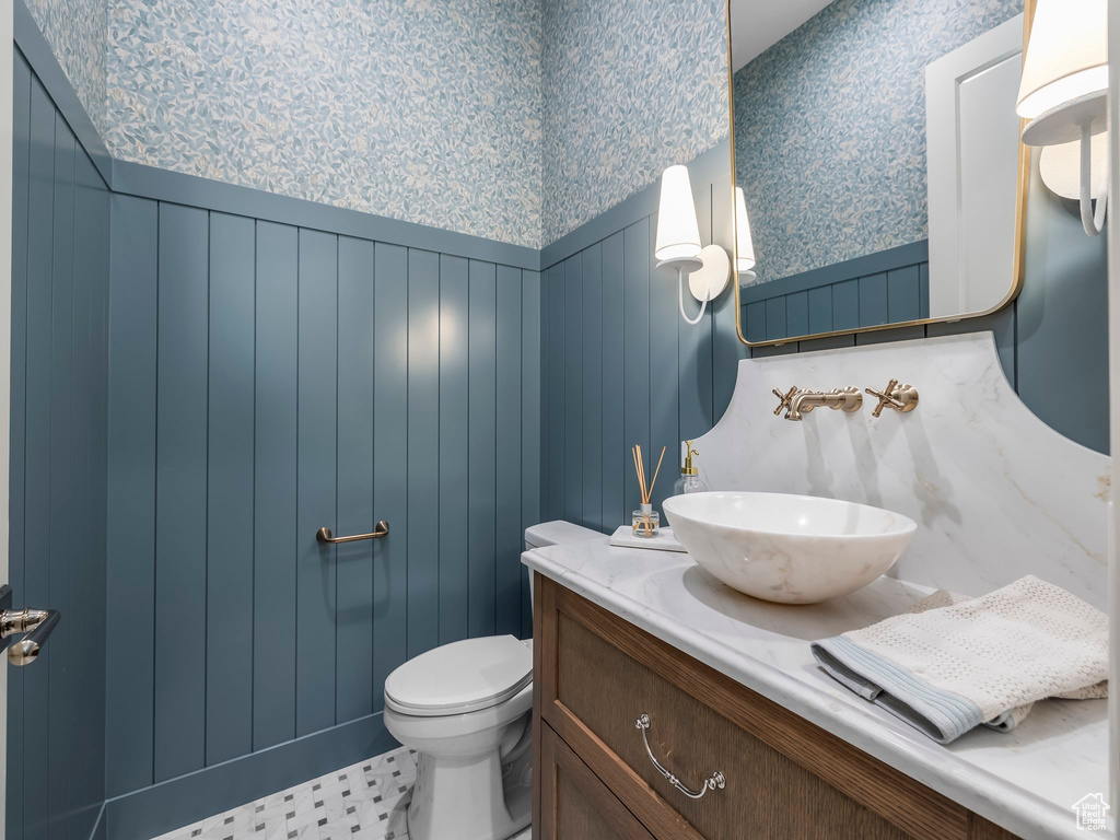 Bathroom featuring wallpapered walls, a wainscoted wall, vanity, and toilet