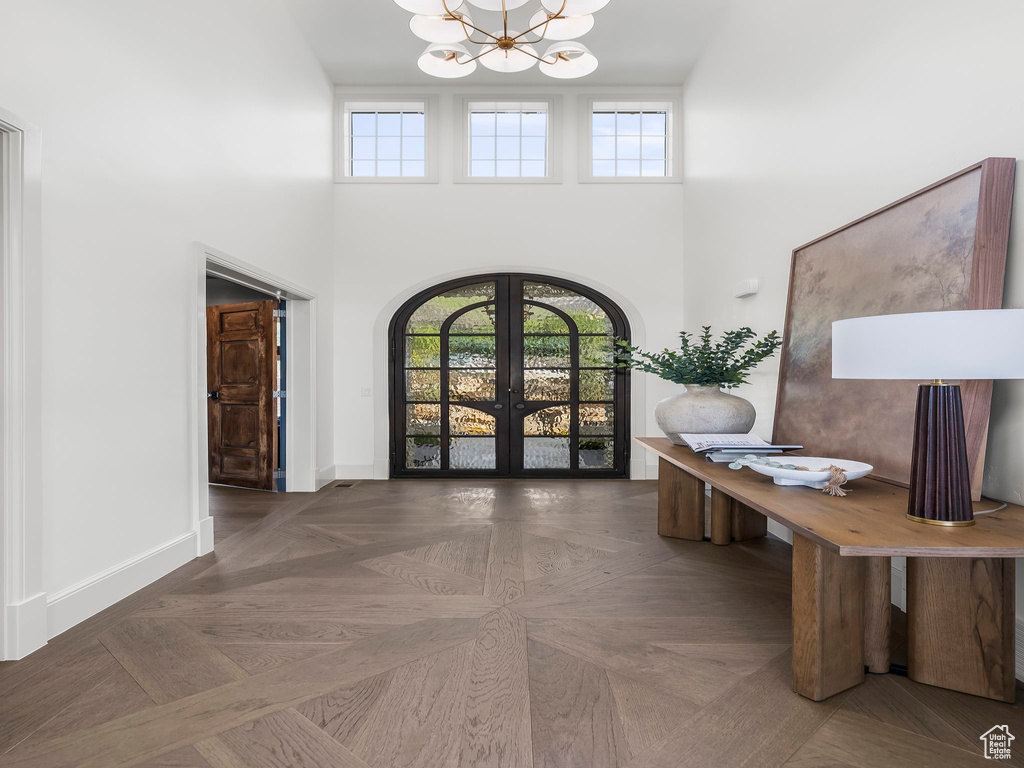 Entryway featuring french doors, a chandelier, a towering ceiling, arched walkways, and healthy amount of natural light
