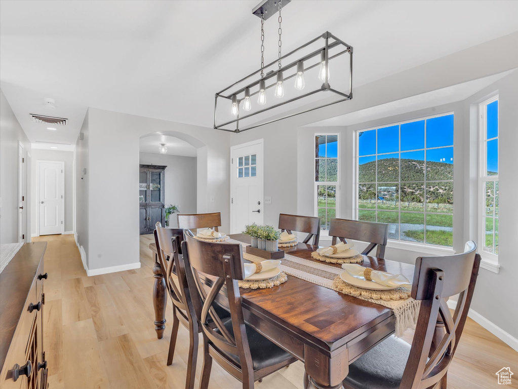 Dining room featuring arched walkways, baseboards, and light wood-style floors