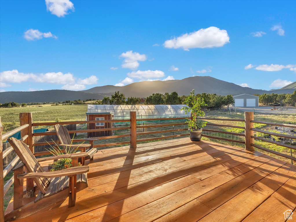 Wooden terrace featuring a mountain view, an exterior structure, and an outbuilding