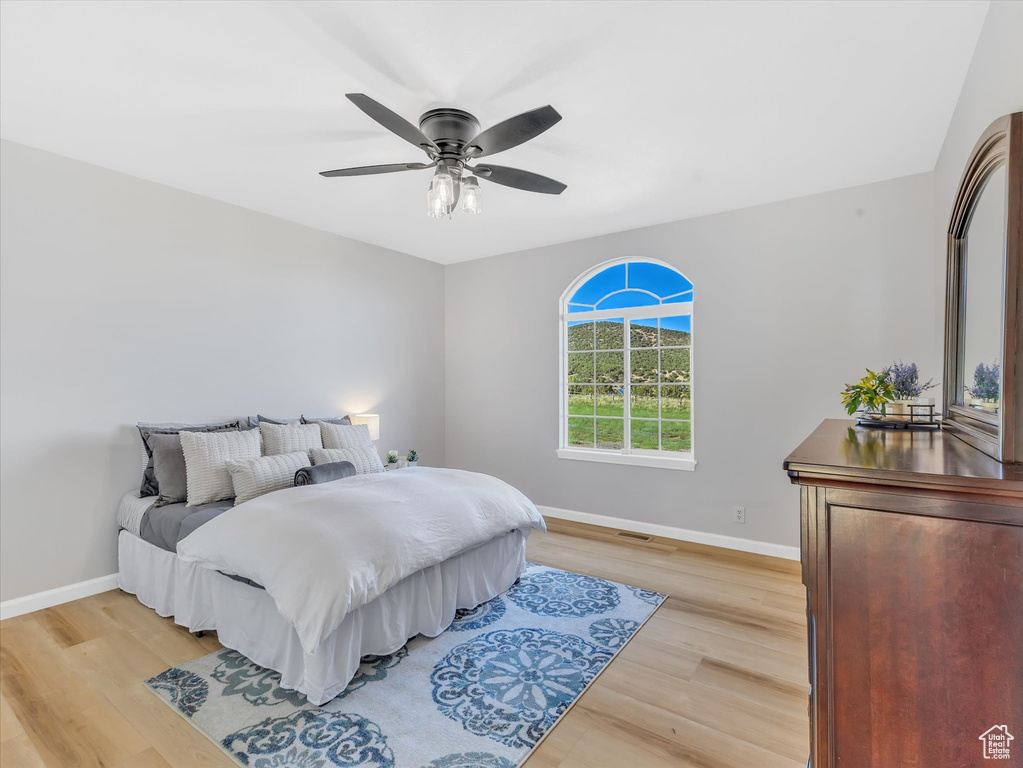 Bedroom featuring baseboards, light wood-style flooring, and a ceiling fan