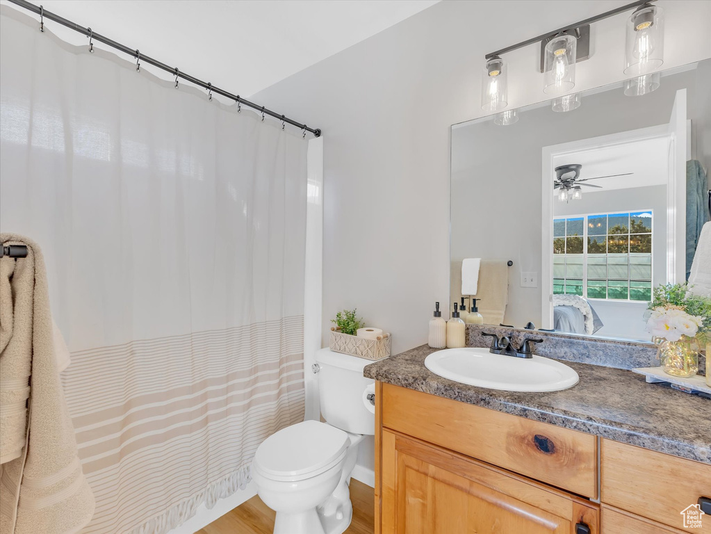 Ensuite bathroom with vanity, toilet, a ceiling fan, wood finished floors, and a shower with curtain