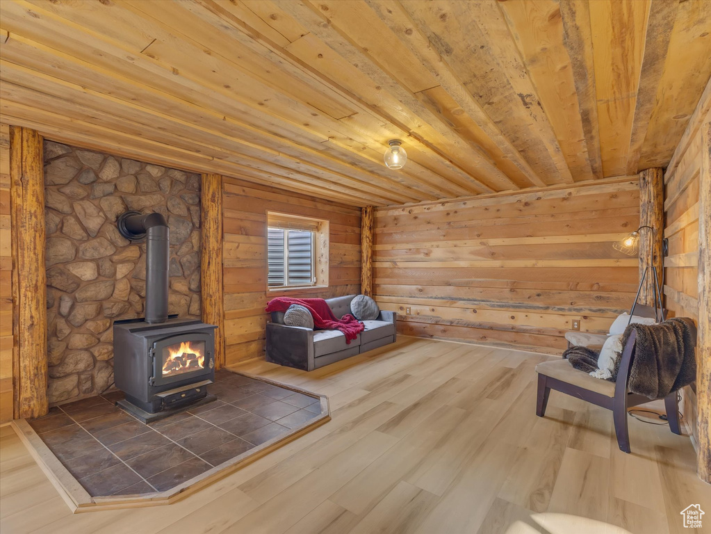 Unfurnished room with a wood stove, wooden ceiling, wood finished floors, and wood walls