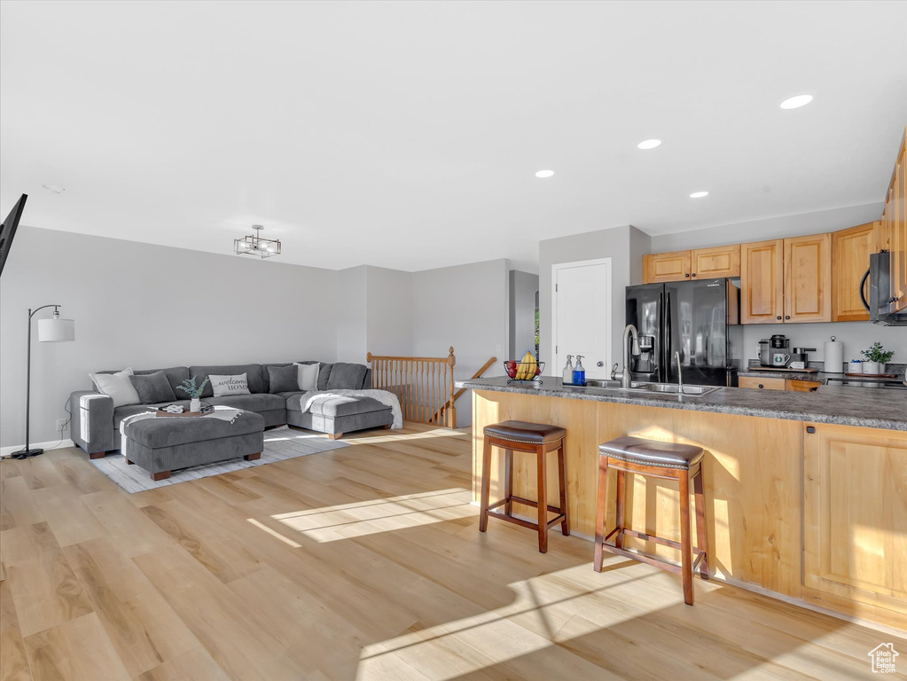 Kitchen featuring black appliances, light wood-style floors, a kitchen bar, a peninsula, and recessed lighting