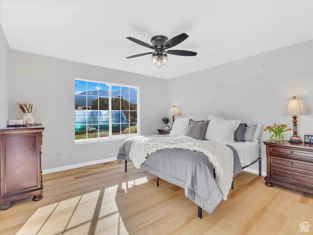 Bedroom featuring baseboards, light wood-style floors, and a ceiling fan