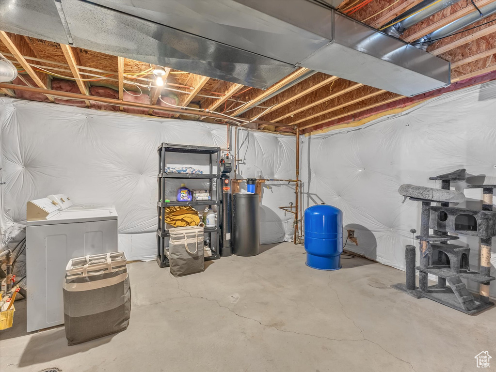 Unfinished below grade area featuring independent washer and dryer and a water pressure tank