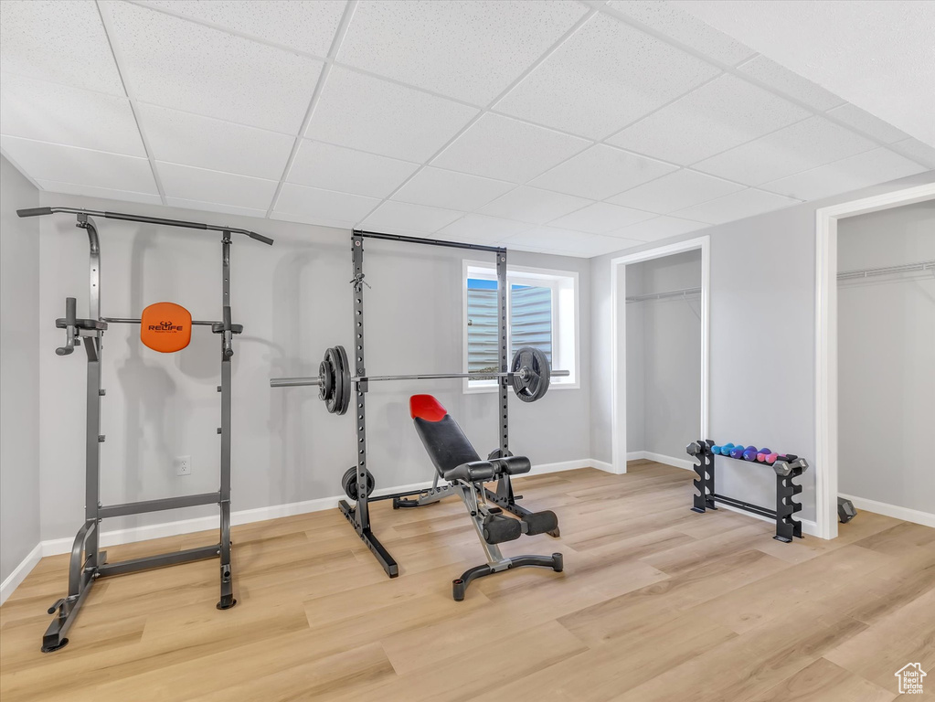 Workout room featuring wood finished floors, baseboards, and a drop ceiling