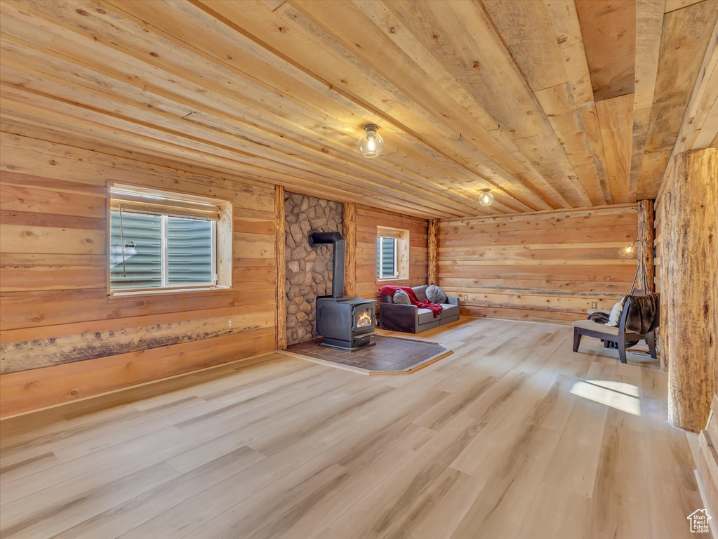 Sitting room featuring a wood stove, wood ceiling, wood finished floors, wooden walls, and healthy amount of natural light