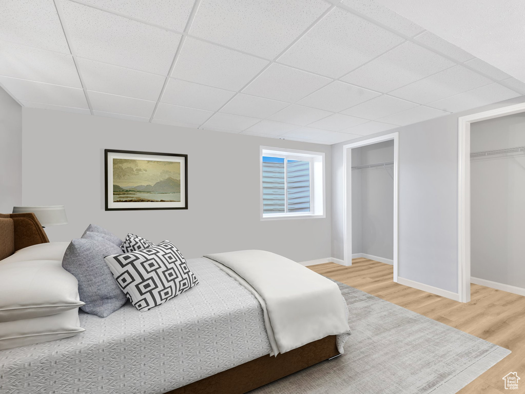 Bedroom with light wood-type flooring and a drop ceiling