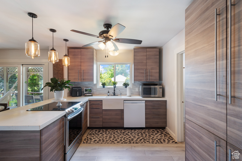 Kitchen with appliances with stainless steel finishes, modern cabinets, and brown cabinets