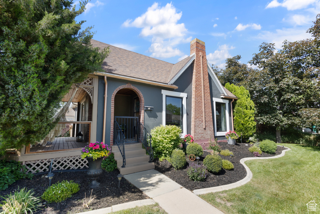 View of front of property with a front yard, a chimney, and roof with shingles
