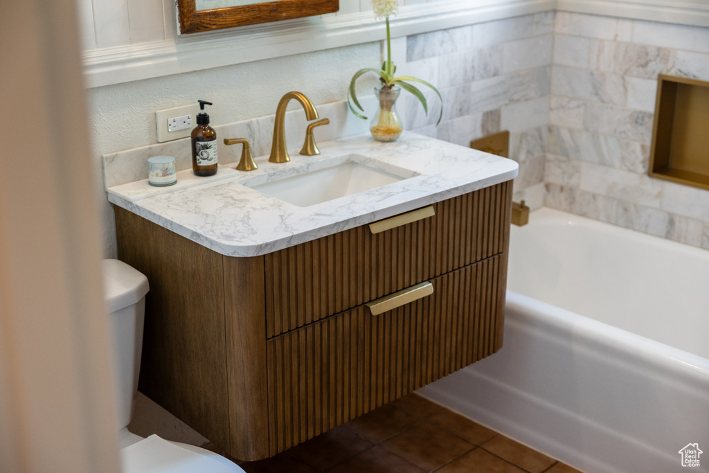 Bathroom with toilet, a tub to relax in, vanity, and tile patterned flooring