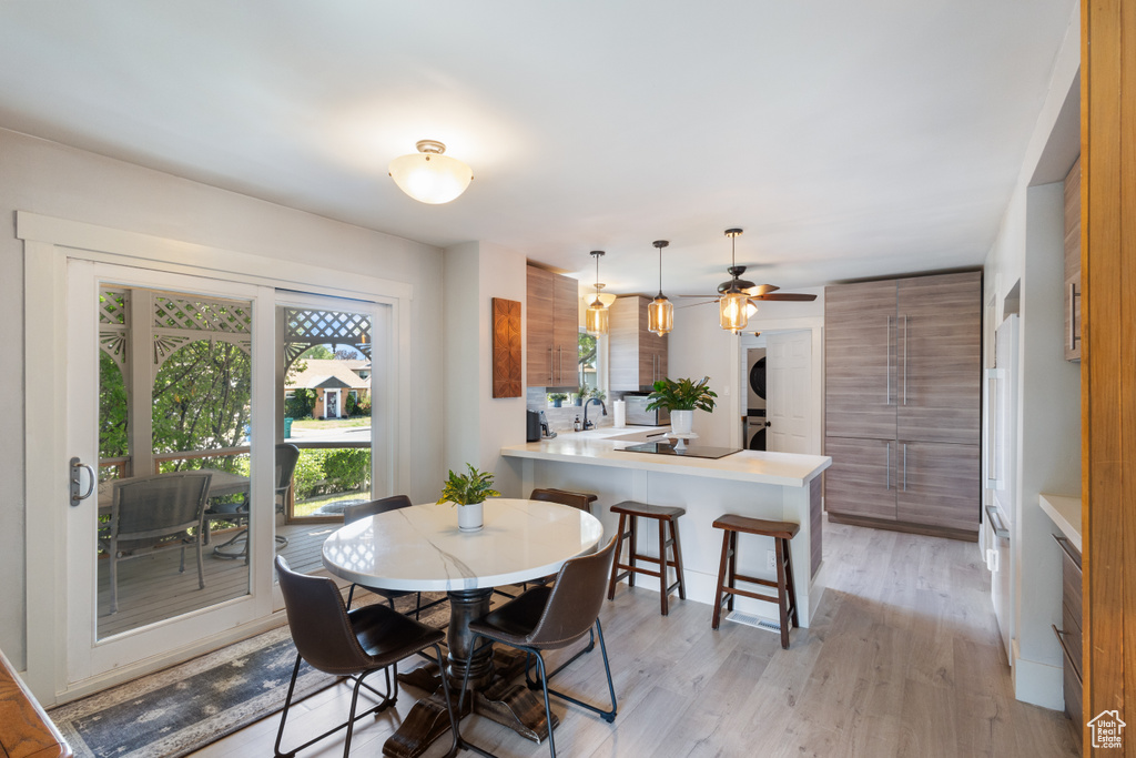 Dining space featuring estacked washer and dryer, light wood finished floors, and ceiling fan
