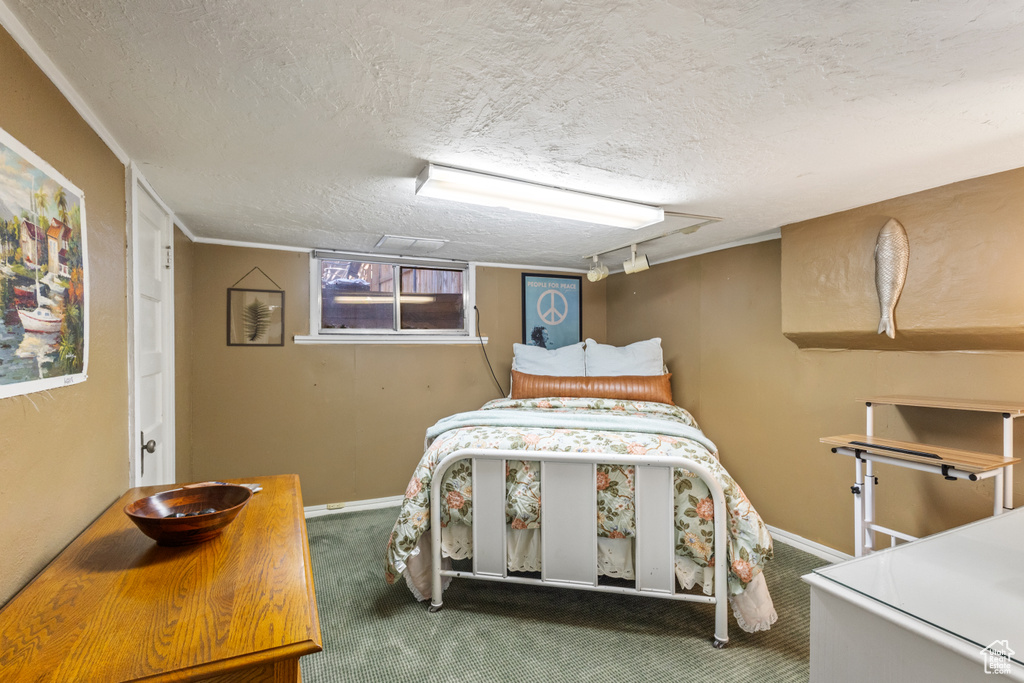 Carpeted bedroom featuring baseboards and a textured ceiling