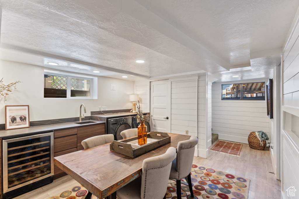 Dining area with wine cooler, a textured ceiling, light wood finished floors, wet bar, and recessed lighting