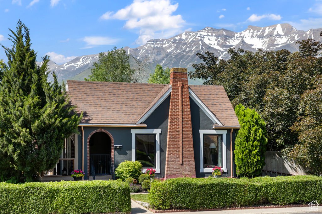 View of front of house with a chimney, a mountain view, stucco siding, and a shingled roof