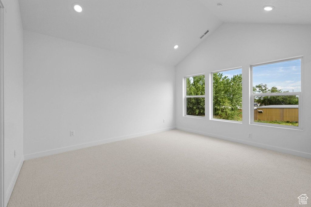 Empty room featuring light colored carpet, recessed lighting, baseboards, and high vaulted ceiling