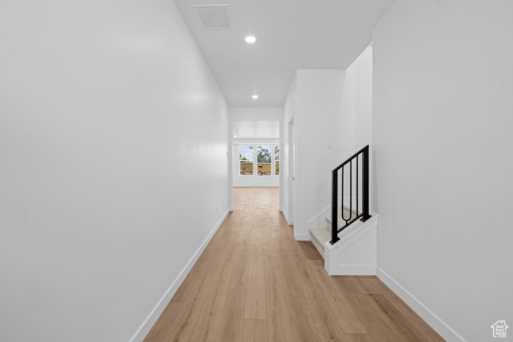 Hall featuring light wood-style flooring, baseboards, recessed lighting, and stairs