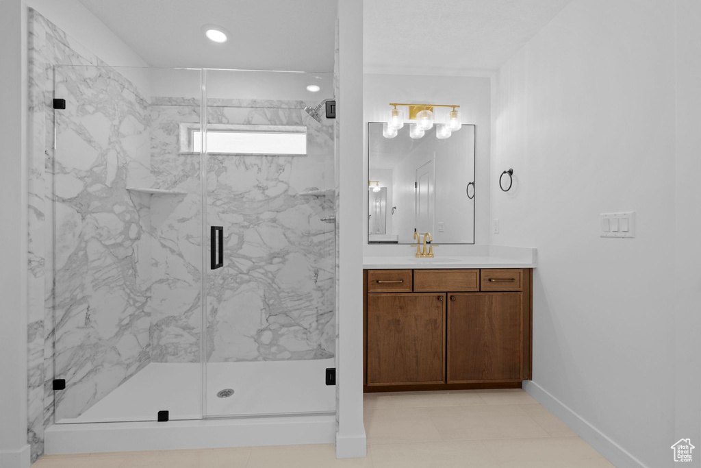 Bathroom with vanity, baseboards, a marble finish shower, and recessed lighting