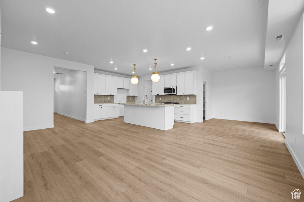 Kitchen with stainless steel microwave, open floor plan, baseboards, recessed lighting, and a sink