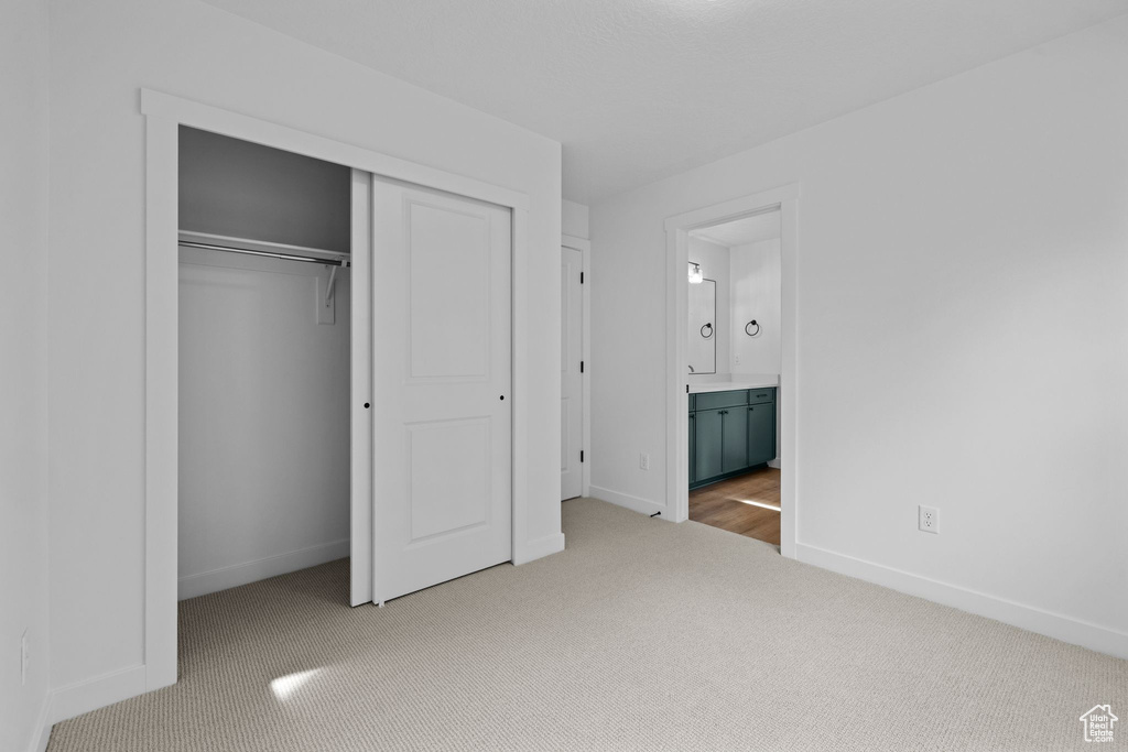 Unfurnished bedroom featuring carpet floors, baseboards, a closet, and ensuite bathroom