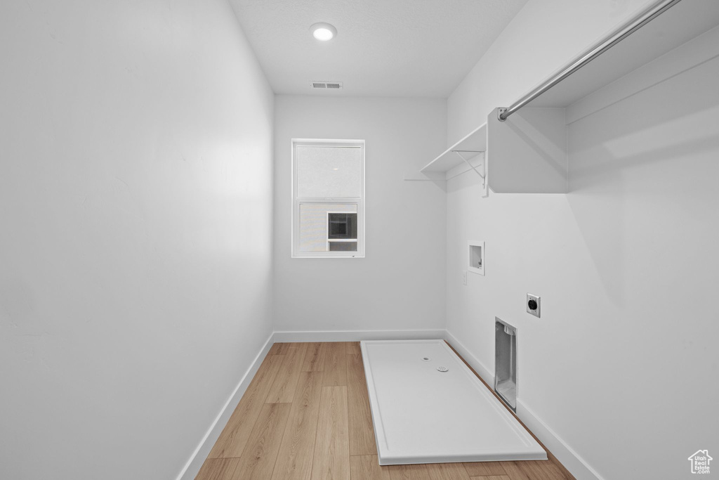 Washroom with hookup for an electric dryer, hookup for a washing machine, baseboards, light wood-style flooring, and recessed lighting